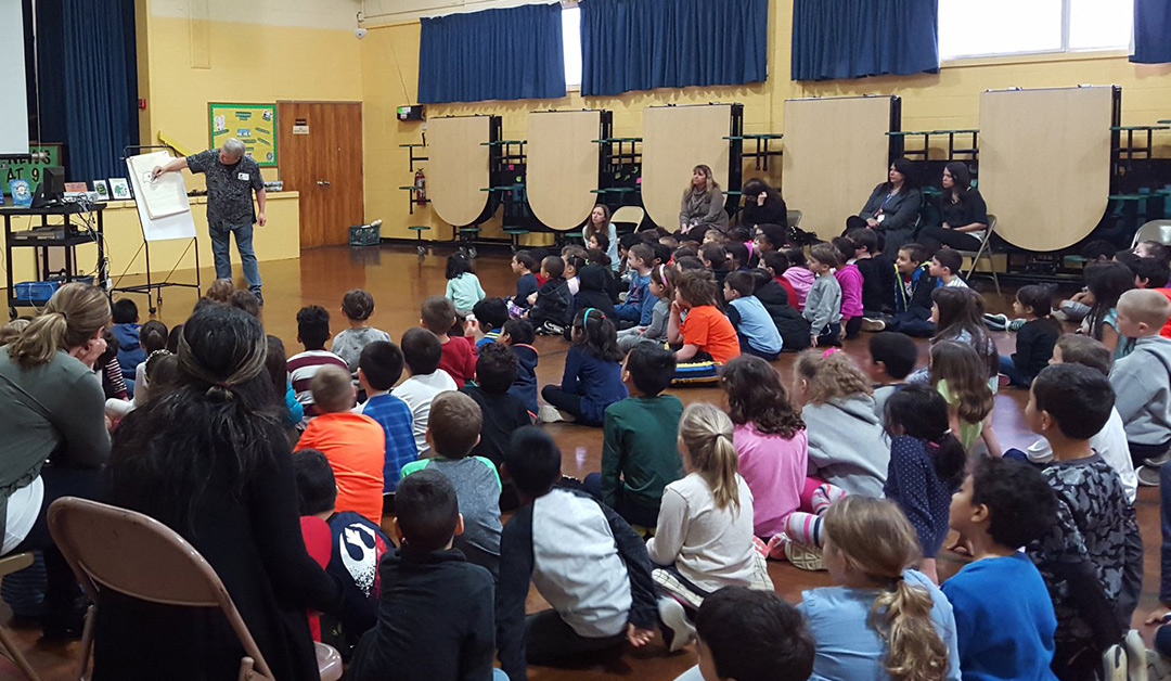 Author/illustrator Timothy Young draws his puffin character at an elementary school assembly.
